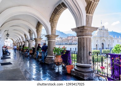 Antigua, Guatemala - April 10, 2019: View Of San José Cathedral & Central Park Through Arches On City Hall Terrace With Purple Lent Banners In Colonial City & UNESCO World Heritage Site Of Antigua.