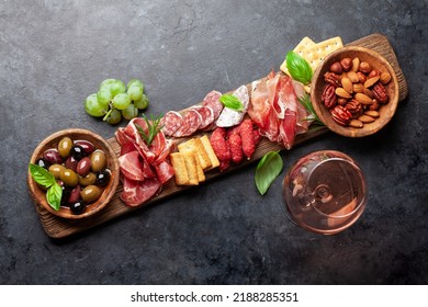 Antipasto board with prosciutto, salami, crackers, cheese, nuts, olives and rose wine. Top view flat lay - Powered by Shutterstock