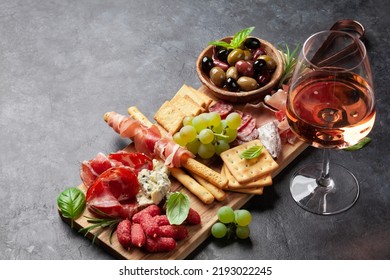 Antipasto board with prosciutto, salami, crackers, cheese, nuts, olives and rose wine. With copy space - Powered by Shutterstock