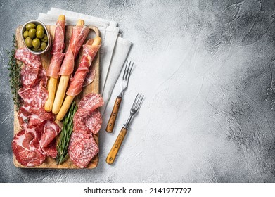 Antipasto platter cold meat plate with grissini bread sticks, Prosciutto crudo, Salami and Coppa Sausage. White background. Top view. Copy space.