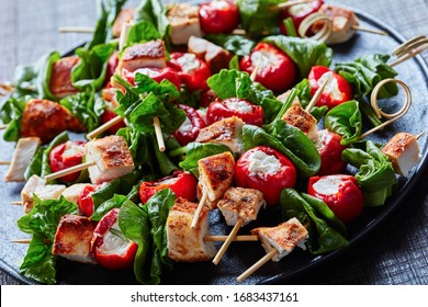 Antipasto skewers of cream cheese stuffed peppers with roasted chicken breasts and spinach on a black plate on a dark wooden background, horizontal view, close-up   - Shutterstock ID 1683437161