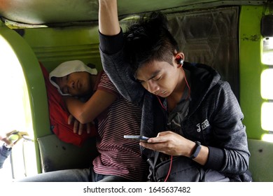 Antipolo City, Philippines - February 13, 2020: Commuters Sleep And Use Smartphone Inside A Passenger Jeep.