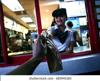 ANTIPOLO CITY, PHILIPPINES - JULY 17, 2017: A Fast Food Chain Worker Gives A Customer A Purchased Product At A Drive Thru.