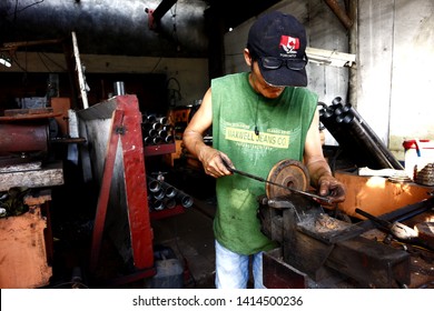 ANTIPOLO CITY, PHILIPPINES – MAY 31, 2019: A worker at a machine shop works on a car spare part and fixes it for a customer.
