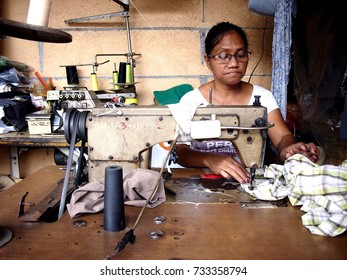 ANTIPOLO CITY, PHILIPPINES - OCTOBER 11, 2017: A dressmaker works on a dress for a customer insider her shop.