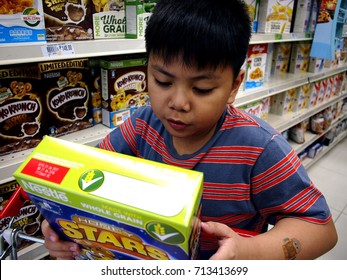 ANTIPOLO CITY, PHILIPPINES - SEPTEMBER 10, 2017: A Young Boy Reads The Label Of A Cereal Box At A Grocery Store.