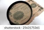 Antique 500-ruble banknote from 1918 under a magnifying glass. A fragment of an ancient imperial 500-ruble banknote dated 1918, viewed through a magnifying glass. 