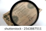 Antique 500-ruble banknote from 1918 under a magnifying glass. A close-up of an antique 500-ruble banknote issued in 1918, viewed through a magnifying glass.