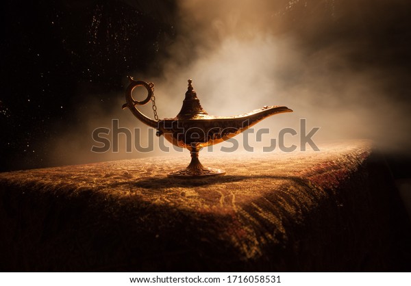 Antique\
Aladdin arabian nights genie style oil lamp with soft light white\
smoke, Dark background. Lamp of wishes\
concept