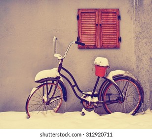 an antique bike with an empty pot on the seat in winter covered in snow toned with a retro vintage instagram filter app or action effect  - Powered by Shutterstock