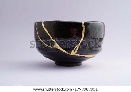 Antique black and gold Kintsugi bowl. Gold cracks restoration on old Japanese pottery restored with the antique restoration technique.The unique beauty of imperfections. 