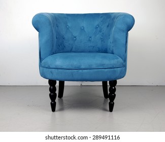 An Antique Blue Velvet Chair Near A White Wall