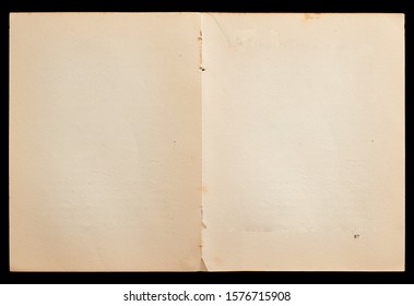 Antique book unfolded showing textured pages isolated on black background.