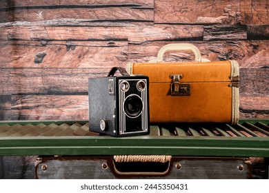 antique box camera and vintage suitcase on green shutter with wood background - Powered by Shutterstock