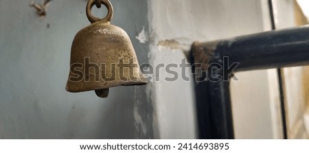 An antique brass bell as a calling signal hanging near the gate