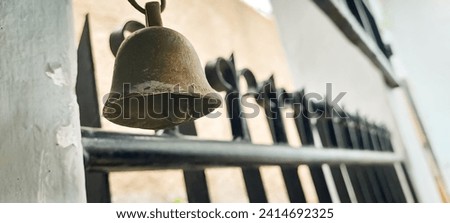 Antique brass bell hanging near the black iron gate