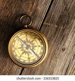 Antique brass compass over wooden background - Shutterstock ID 136313825