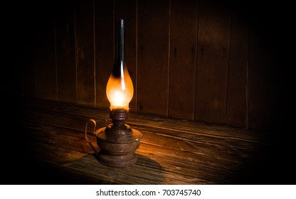 Antique burning paraffin lamp near on the wooden table.