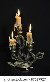 Antique Candelabra With Three Melting Candles On Black Background