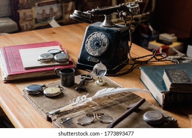 antique desk with accessories: old telephone, books, globe, notes, ink pen, old glasses. and for hours. The picture conveys the atmosphere of antiquity - past years
