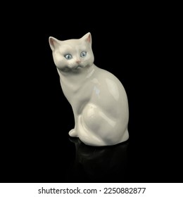 antique figurine of a cat on a black isolated background. kitten toy. vintage porcelain cat figurine