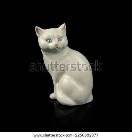 antique figurine of a cat on a black isolated background. kitten toy. vintage porcelain cat figurine