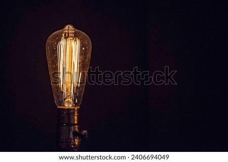 Antique Filament Glowing Incandescent Light bulb Tungsten isolated on black background clear glass Edison Bulb