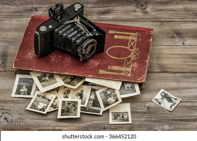 Antique Film Camera And Photo Album With Old Pictures On Wooden Table