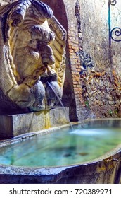 Antique Fountain On The Wall Of Parco Savello In Aventine, Also Known As Orange Garden, Rome - Italy. Night View Of The Famous Sculpture In Marble And Granite. 