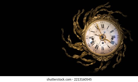 Antique antique gold-framed clock with Roman numerals and a symbolic snake on the dial in fancy gilt decoration in the form of the sun, isolated on a black background - Shutterstock ID 2213160545