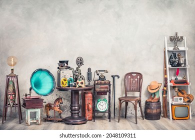 Antique gramophone, chair, retro microphone and recorder on table. Old telephone, typewriter, radio, TV on shelving front concrete wall background. Nostalgic still life. Vintage style filtered photo - Shutterstock ID 2048109311