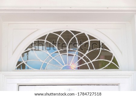An antique half-circle decorative transom window in a federalist building.
