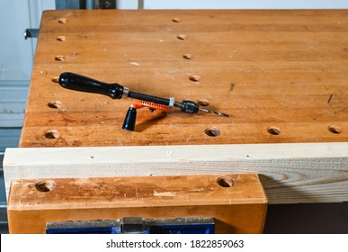 Antique Hand Crank Drill And Bit Sitting On A Maple Workbench.  Wood Clamped In Vise 