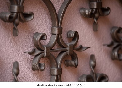 Antique handcrafted wrought iron entrance gate railing against a pink stucco wall in Barr, Alsace France. 