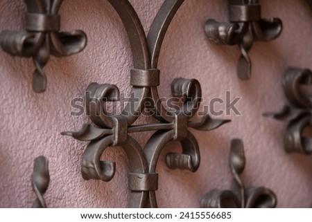 Antique handcrafted wrought iron entrance gate railing against a pink stucco wall in Barr, Alsace France. 