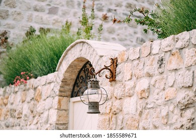 An antique hanging lantern on a rusty hook on a stone fence in Perast, Montenegro.
