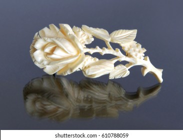 Antique Ivory carved brooch Rose on gray background with mirror reflection