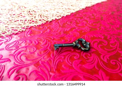 An Antique Key Placed On A Red Tablecloth. White Table Runner Placed On The Red Tablecloth. A Key That Can Open Magical Door.
