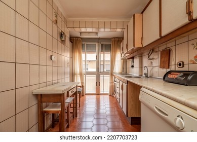 Antique Kitchen With Edge Wood Cabinets, Folding Table With Stools, Bay Window In Back, And Light Brown Flooring