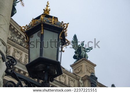 Antique lamp post near Lviv State Academic Opera and Ballet Theatre. Theatre was built in classical tradition of Renaissance and Baroque architecture. The building is crowned by large bronze statue.
