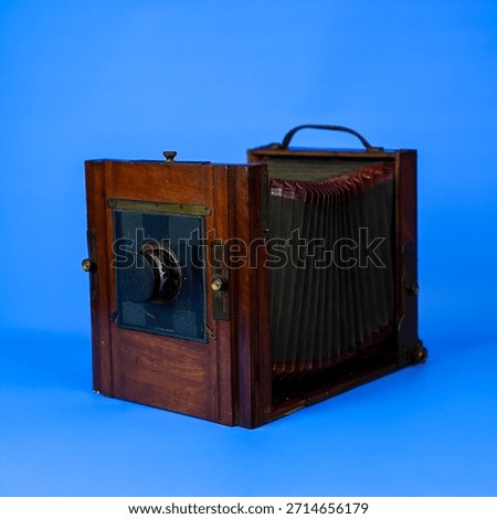 Antique Large Format Folding Bellows Camera Close-Up: Vintage Wooden Box Camera for Historic Photography and Collection on Isolated Blue Studio Background