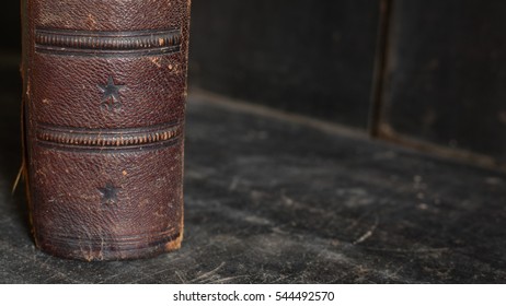 Antique Leather Bound Book Standing Alone On An Old Wooden Bookshelf