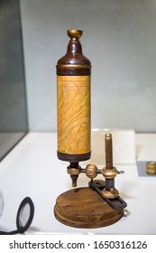 Antique Leeuwenhoek microscope in light brown on a white table, Microbiology scientific instruments.
