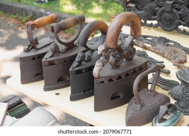 Antique metal coal irons and other vintage items on flea market or festival. Collectibles memorabilia concept. Vintage handle iron. Selective focus