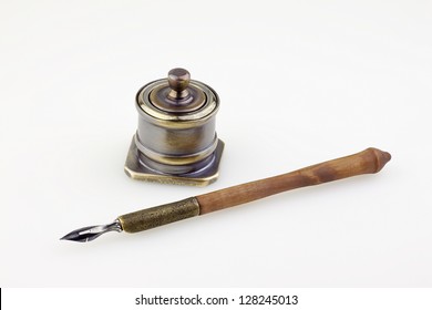 An antique metallic inkwell and old pen isolated background