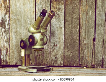 Antique microscope on a grunge wood backdrop with copy space.