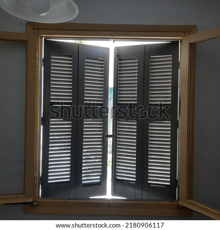 Antique old wooden window frame and window shutters with streaming light. Indoor view of window shutter