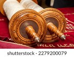 Antique parchment Torah scrolls lie on a red velvet bedspread on which our teacher is written in Hebrew