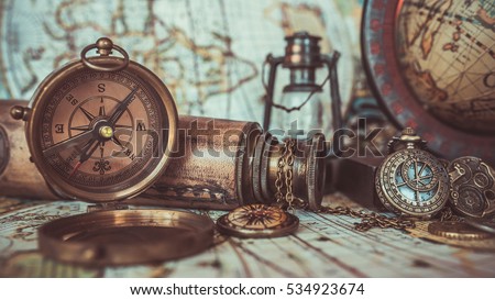 Antique pirate rare items collections including with a bronze pocket compass with cover lid, old binoculars, compass necklace, world globe base on ancient world map background.  (vintage style)