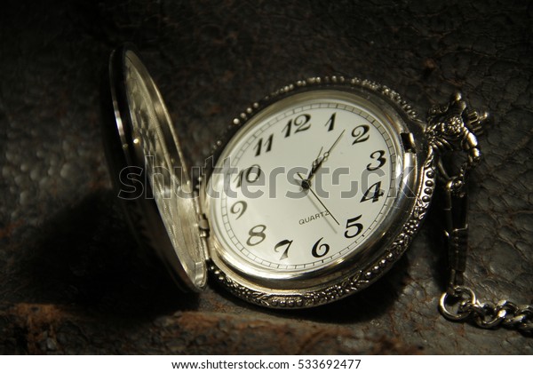 Antique pocket\
watch with chain on dark\
backdrop